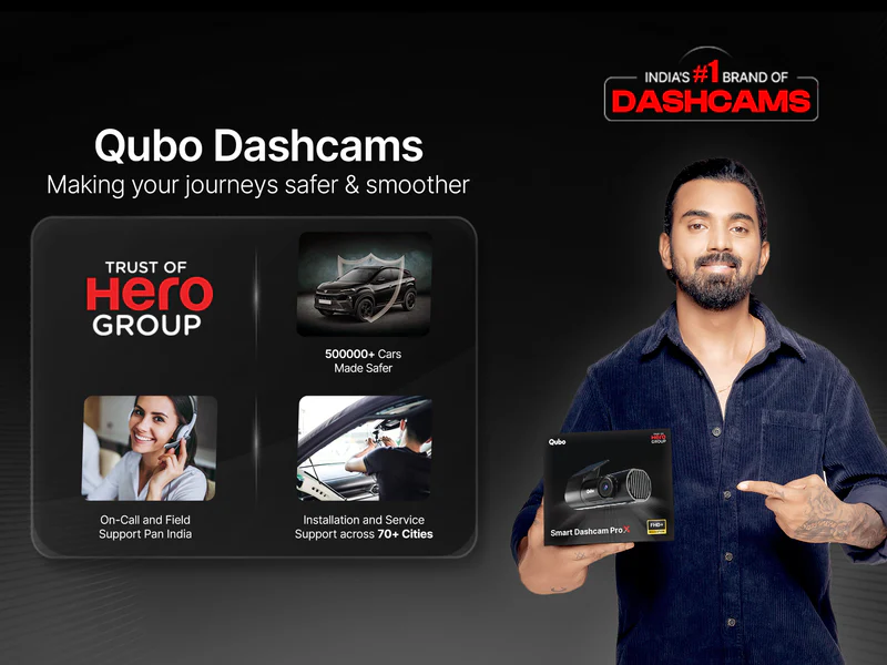 Qubo Dashcams ad featuring a male brand ambassador holding a dashcam box, highlighting safety features, Hero Group trust, and protection against fake accident claims